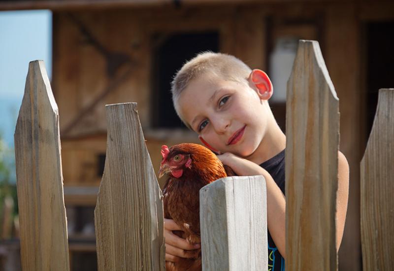 a boy with chicken in his arms